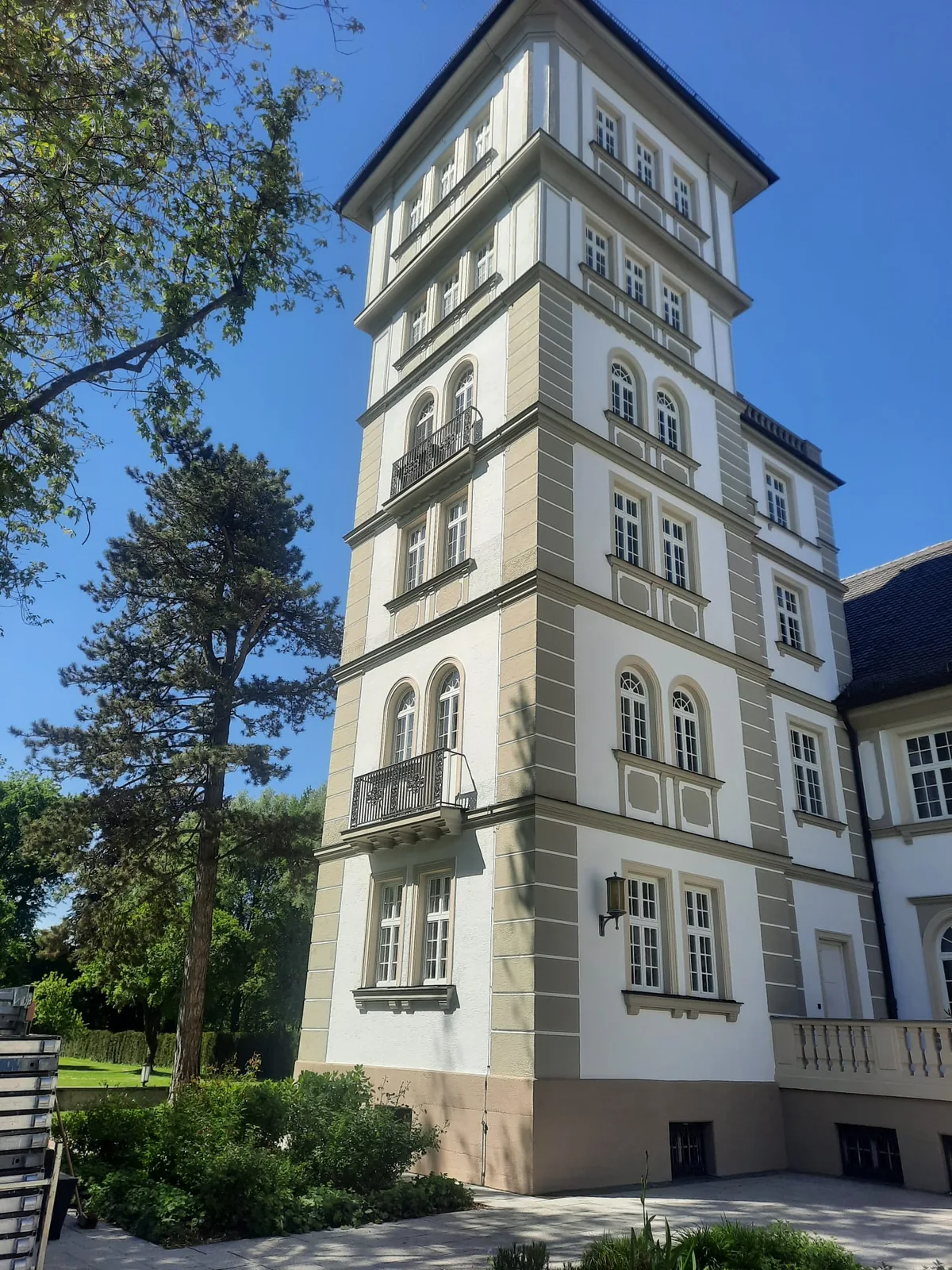 Mehrgeschossiges helles Gebäude mit markantem Turm und vielen Fensterachsen