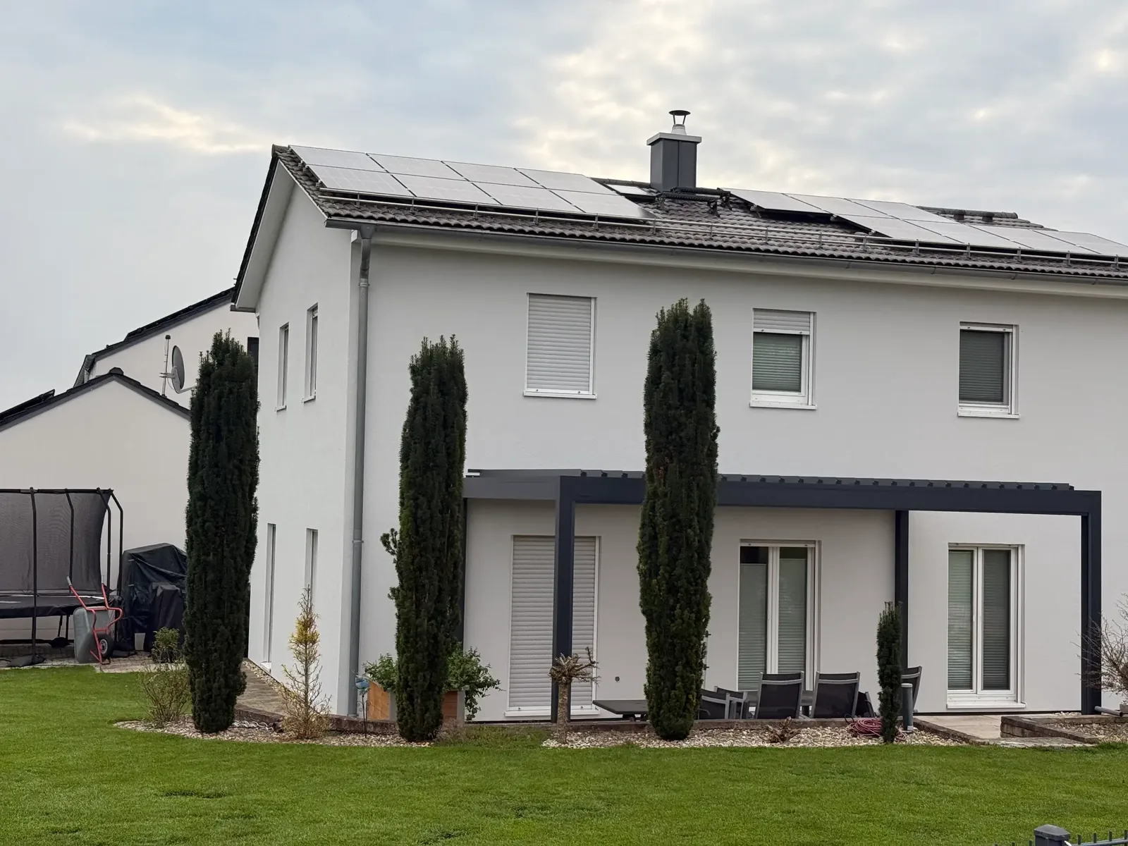 Freistehendes Wohnhaus mit weißer Fassade und grauem Sockelbereich